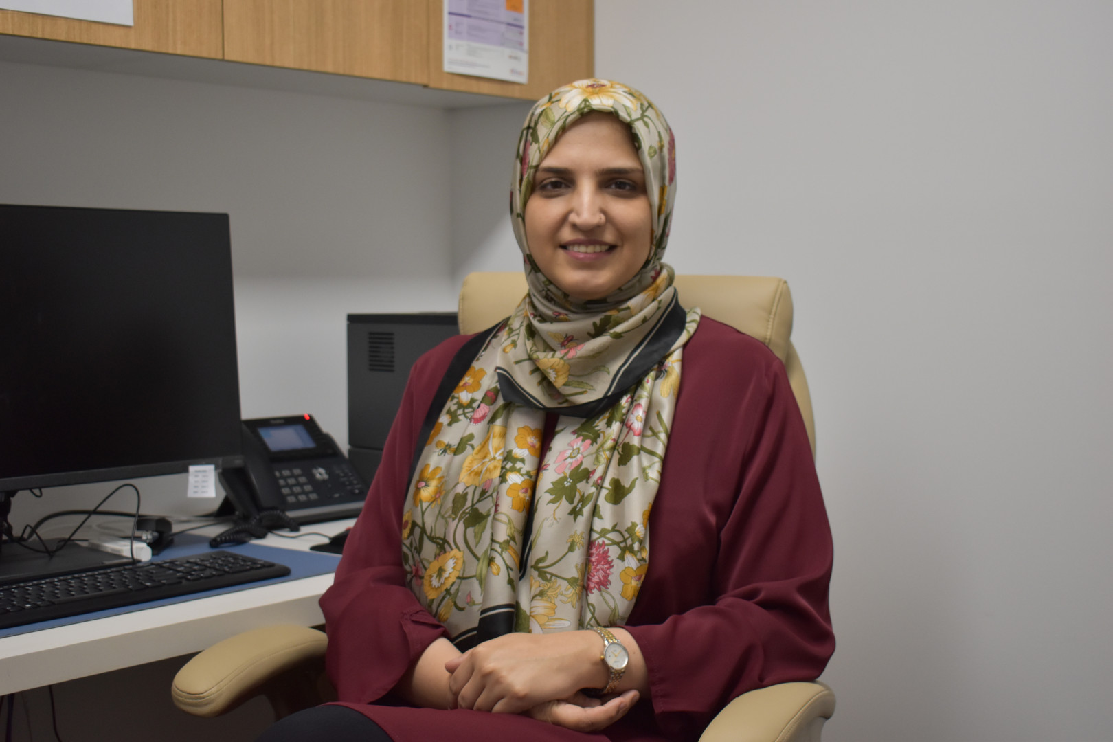 Dr. Fatima Adeel Siddiqi smiling a the camera whilst sitting at her work desk