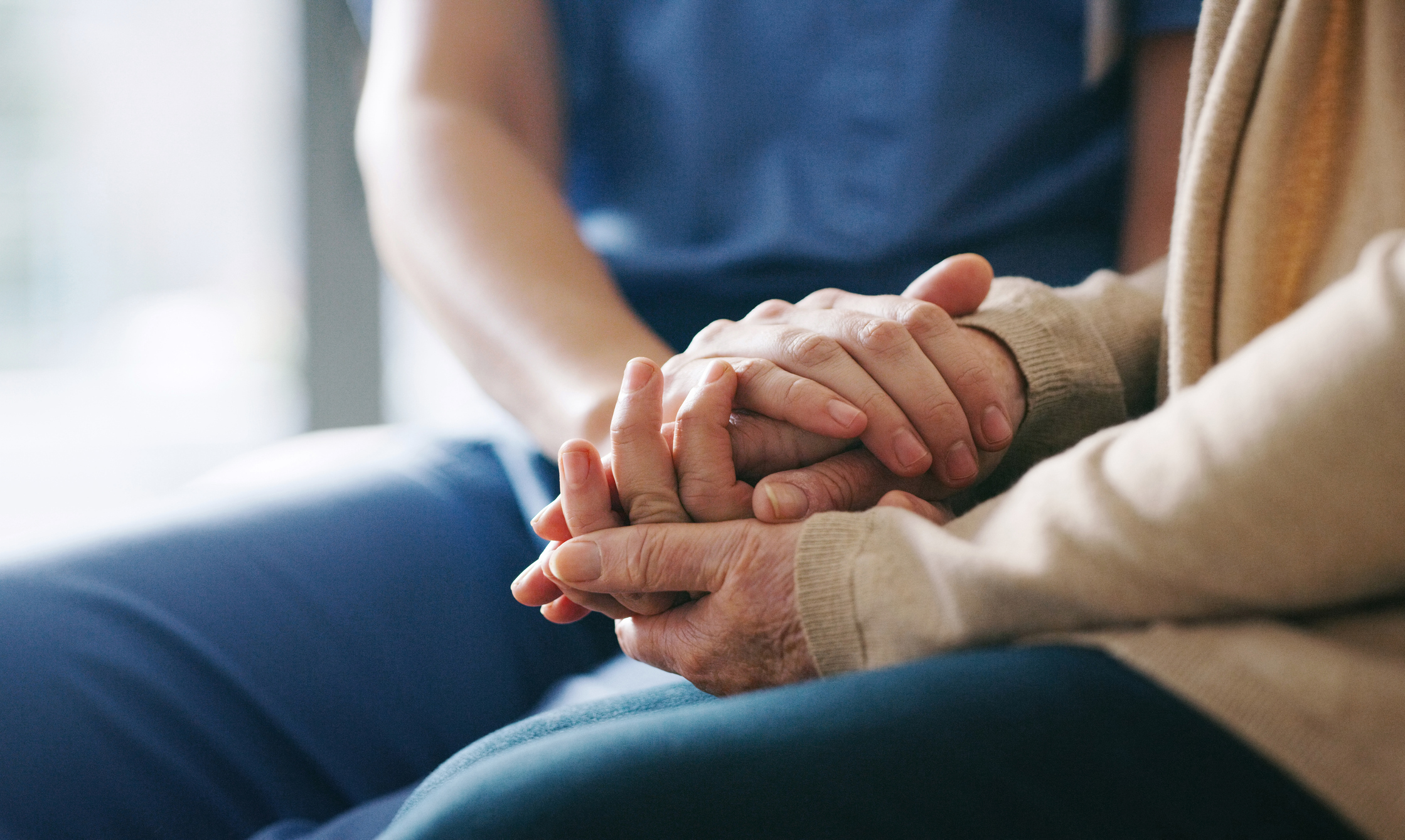 Nurse holding an elderly patients hand