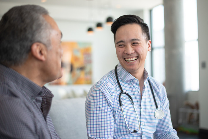 G P smiling and talking to an elderly patient.