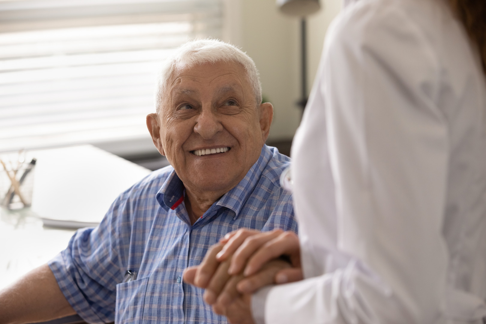 Elderly man smiling whilst sitting in a lounge chair