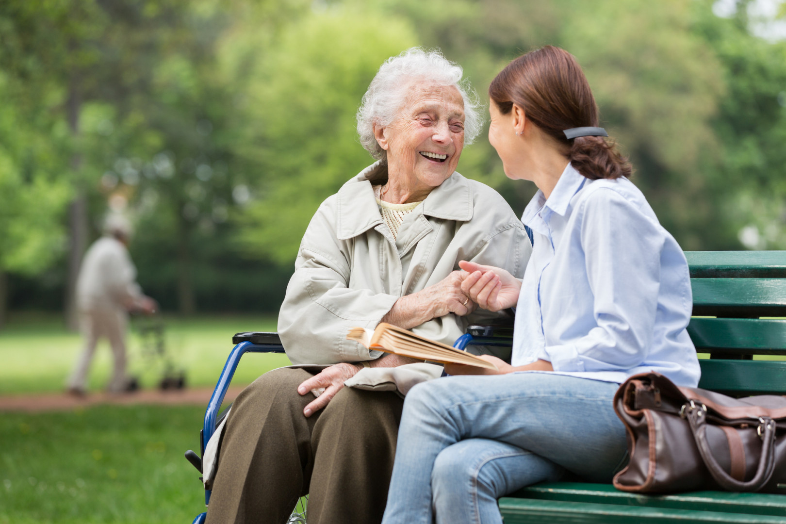 Elderly woman speaking with their carer whilst sitting on a park bench