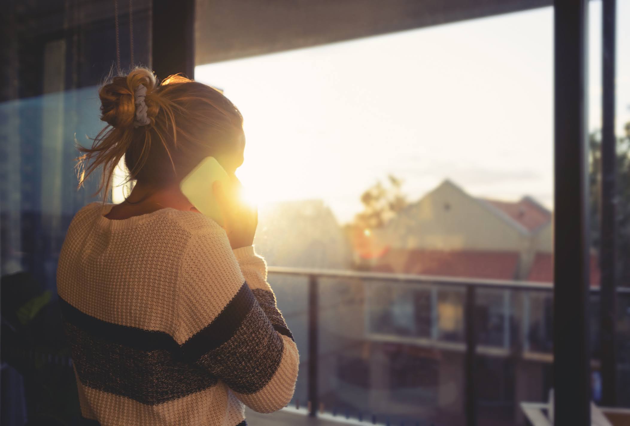 Young woman talking on the phone whilst looking out a window