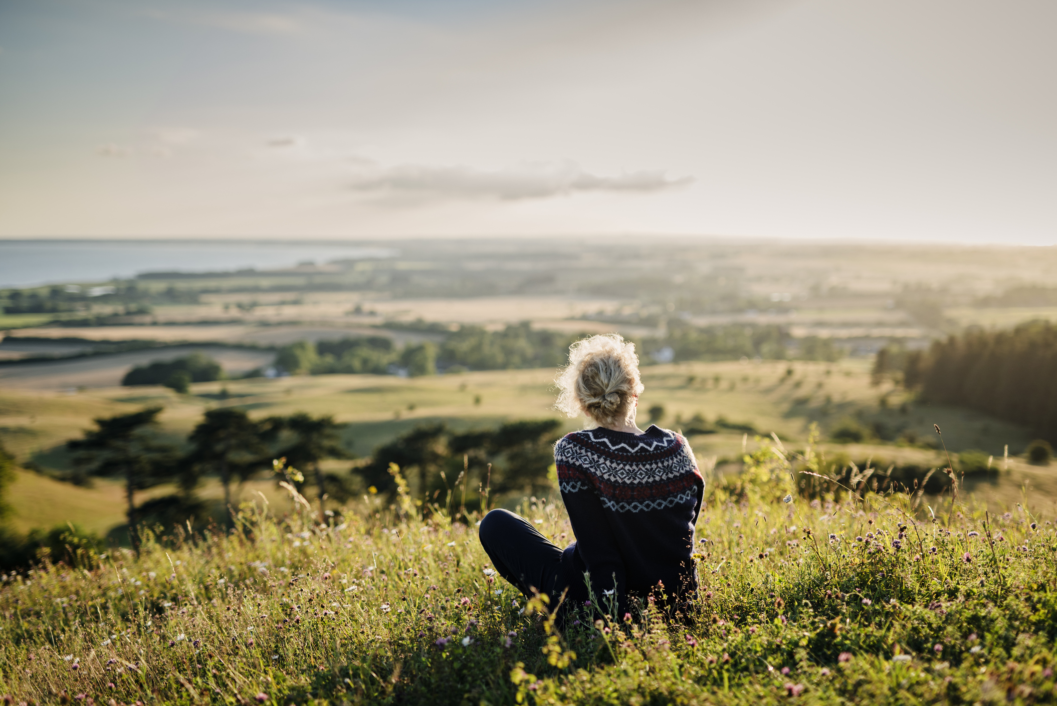 Young woman sitting on a grassy hill looking out over a valley