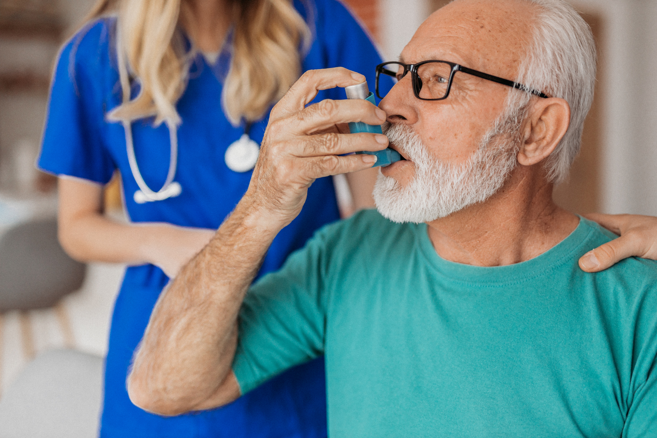 An elderly man receiving support with a puffer from a nurse