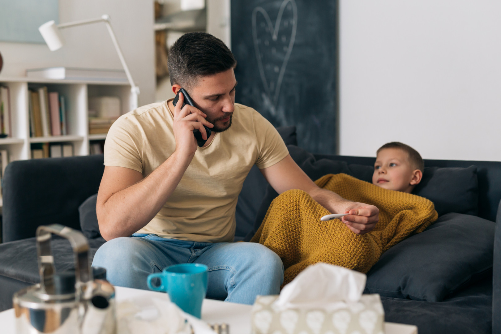 Father on the phone, next to sick child.